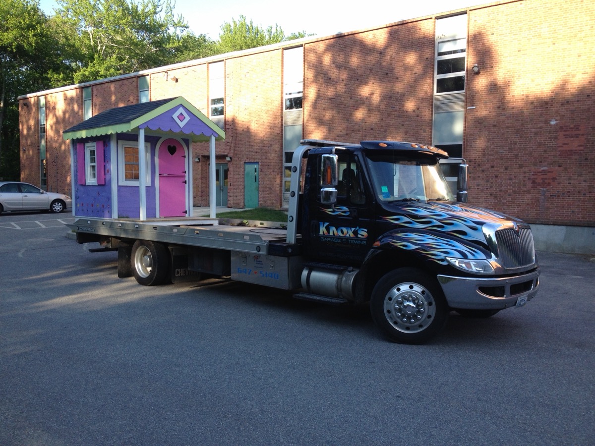 A child's playhouse being transported on a flatbed